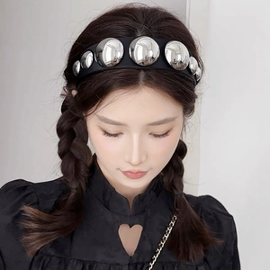 Detail of wide black fabric headband with large silver round metal studs on a model