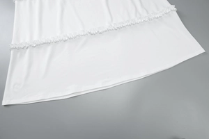 Detailed close-up showing the elegant white ruffle hem and soft fabric texture of the dress