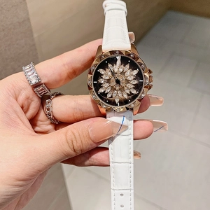 Close-up of women's watch with white leather strap and rotating diamond flower dial