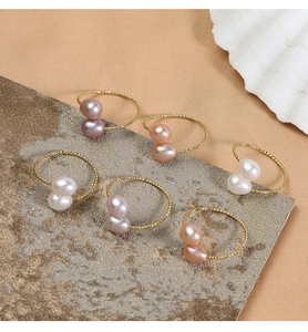 Flat lay of natural freshwater pearl rings in white, pink and purple on golden metal band