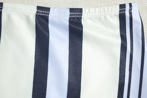 Gros plan sur un tissu rayé noir blanc et bleu avec des détails de double couture