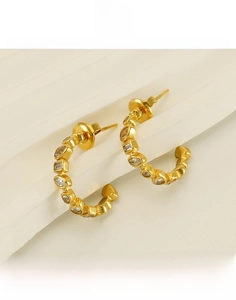 Detail view of 18k gold plated U-shaped titanium earrings with white zircon inlays