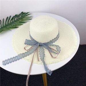 Detail of off-white straw hat featuring light blue lace and LOVE ME DO ribbon decoration