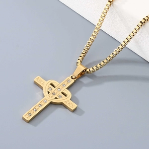 Detailed view of golden cross pendant with heart center and sparkling rhinestones