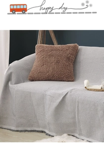 Detail of off-white waffle weave sofa cover and brown plush pillow in a modern home setup