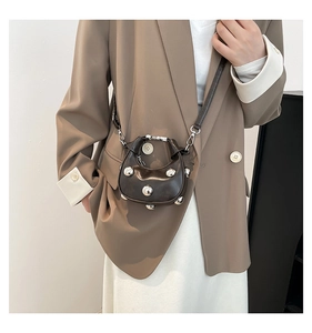 Detail of dark brown mini crescent bag with silver metallic studs worn by a model