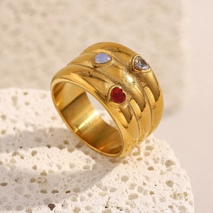 Détail d'une bague large plaquée or 18K avec trois zircons colorés en forme de cœur