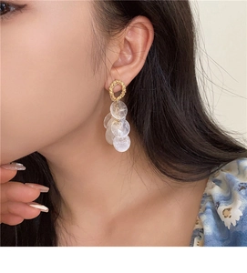 Detail of round shell tassel earrings with gold ring and translucent white resin discs