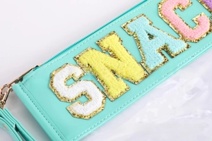 Detail of mint green PVC toiletry bag with SNAC chenille letter patches and gold glitter