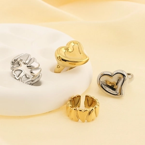 Creative 18K gold and silver stainless steel heart rings on white artistic display