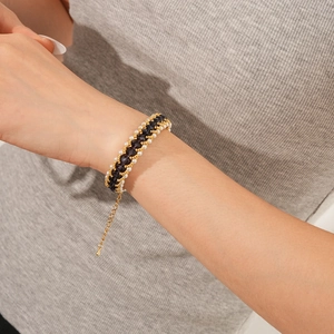 Detail of layered woven bracelet with black faceted beads and pearls on wrist