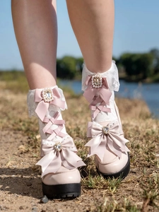 Close-up of white Lolita lace socks with pink ribbon bows and pearl rhinestone details