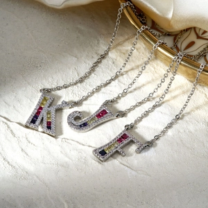 Silver initial letter necklace with colorful cubic zirconia on a minimalist textured base