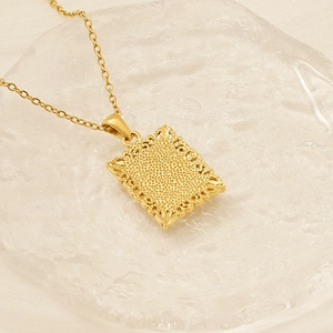 Detailed macro view of a gold square alphabet pendant with a honeycomb texture back