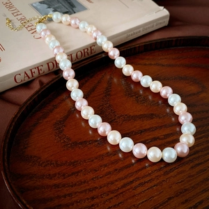 Vue détaillée du collier de perles roses et blanches avec fermoir doré sur plateau