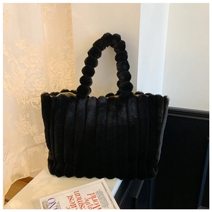 Detailed view of black plush tote bag with vertical stripes and unique ball bead handle