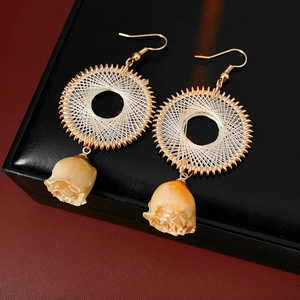 Detail of bohemian gold hoop earrings with beige woven mesh and dried rose bud pendant