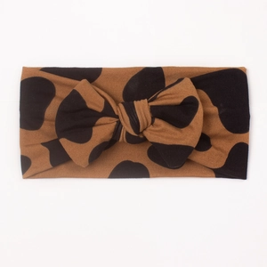 Detail view of baby bow headband with brown and black leopard-style polka dot pattern