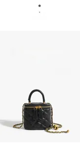 Detail of black quilted mini bag featuring golden metal chain and leather handle