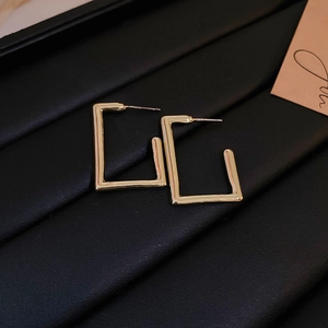 Macro shot of rectangular gold earrings with S925 silver needles on black jewelry display