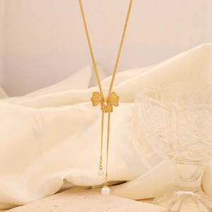Detail of a gold bow pendant with long tassels and pearls on a silk background