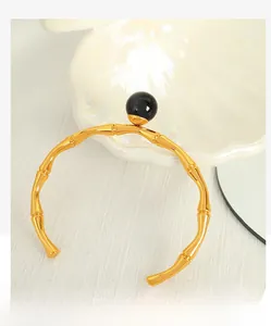 Macro detail of golden bamboo textured open bangle with a large black bead accent