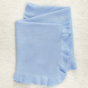 Detail of light blue knitted baby blanket with delicate ruffle edges and soft texture