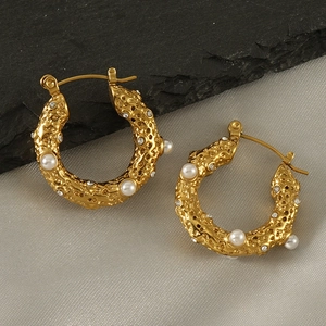 Détail de créoles plaquées or 18k avec petites perles et cristaux sur tissu en soie