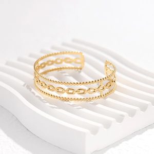 Detailed close-up of golden multi-layer chain design on a stainless steel C-shaped bangle