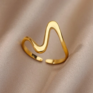 Macro shot of polished gold wave-shaped adjustable open ring on champagne satin