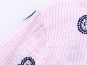 Gros plan détaillé sur tissu à rayures roses avec broderie florale circulaire bleu foncé