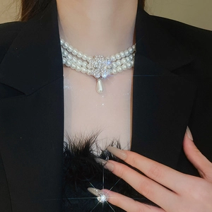 Detail of three-row pearl choker necklace with a crystal floral centerpiece and drop pearl