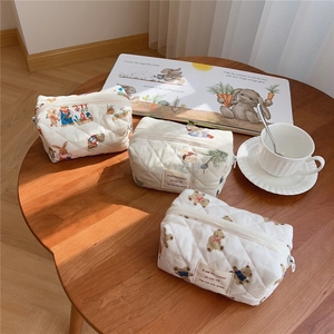 Quilted cotton makeup bag with cute bear pattern on wooden table with coffee cup