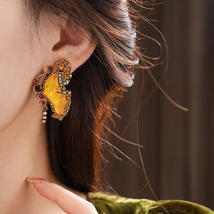 Close-up of vintage butterfly earrings with orange crystals and gold wing detailing