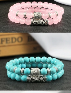 Detail of beaded bracelets featuring pink crystal, turquoise stones, and silver Buddha charms