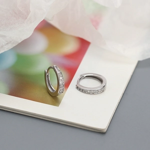 Detailed close-up of S925 silver hoop earrings with a row of inlaid zircons on a notebook