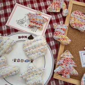 Close-up of handmade knitted Christmas tree, star and apple ornaments in festive setting