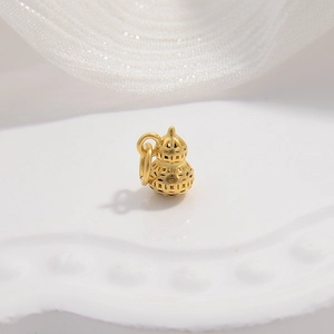 Macro detail of a hollow gold gourd charm with a metal ring and polished finish