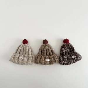 Drei verschiedene Winterstrickmützen mit flauschigen Pompons und Markenetiketten