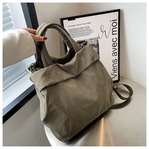 Detailed view of olive green nylon tote bag with wide strap on a metal table