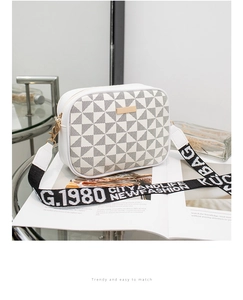 Detail of white camera bag with geometric patterns and a wide jacquard shoulder strap