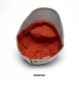 Détail de la casquette plate grise montrant la doublure orange et l'étiquette interne