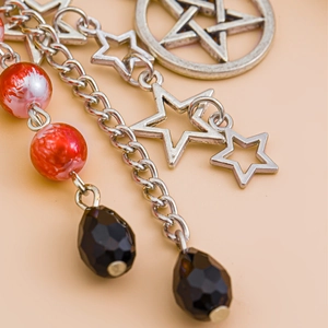 Close-up of silver star pendants with red and black beads on a metal keychain chain