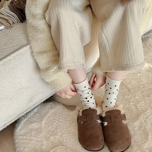 Close-up of brown suede slippers with white faux fur lining and polka dot wool socks