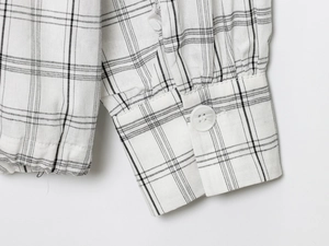 Gros plan du poignet d'une chemise à carreaux noir et blanc avec bouton et couture