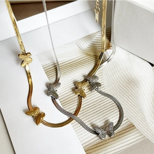 Macro detail of gold and silver herringbone chains with textured butterfly pendants
