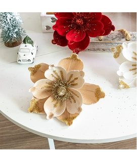 Close-up of velvet Christmas flowers with gold glitter accents on a festive table set