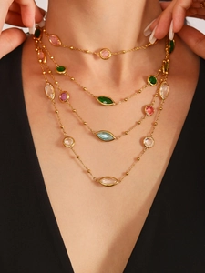 Détail d'un collier doré multicouche avec pierres colorées sur mannequin en tenue noire