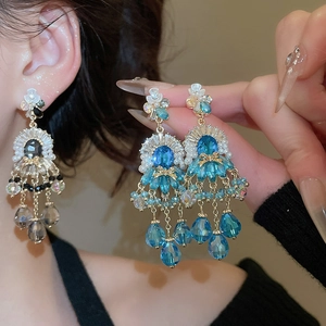 Dettaglio di orecchini a fiore di lusso con nappe di cristallo blu e impostazioni di strass