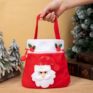 Sac cadeau de Noël rouge avec Père Noël 3D tenu à la main devant un sapin décoré